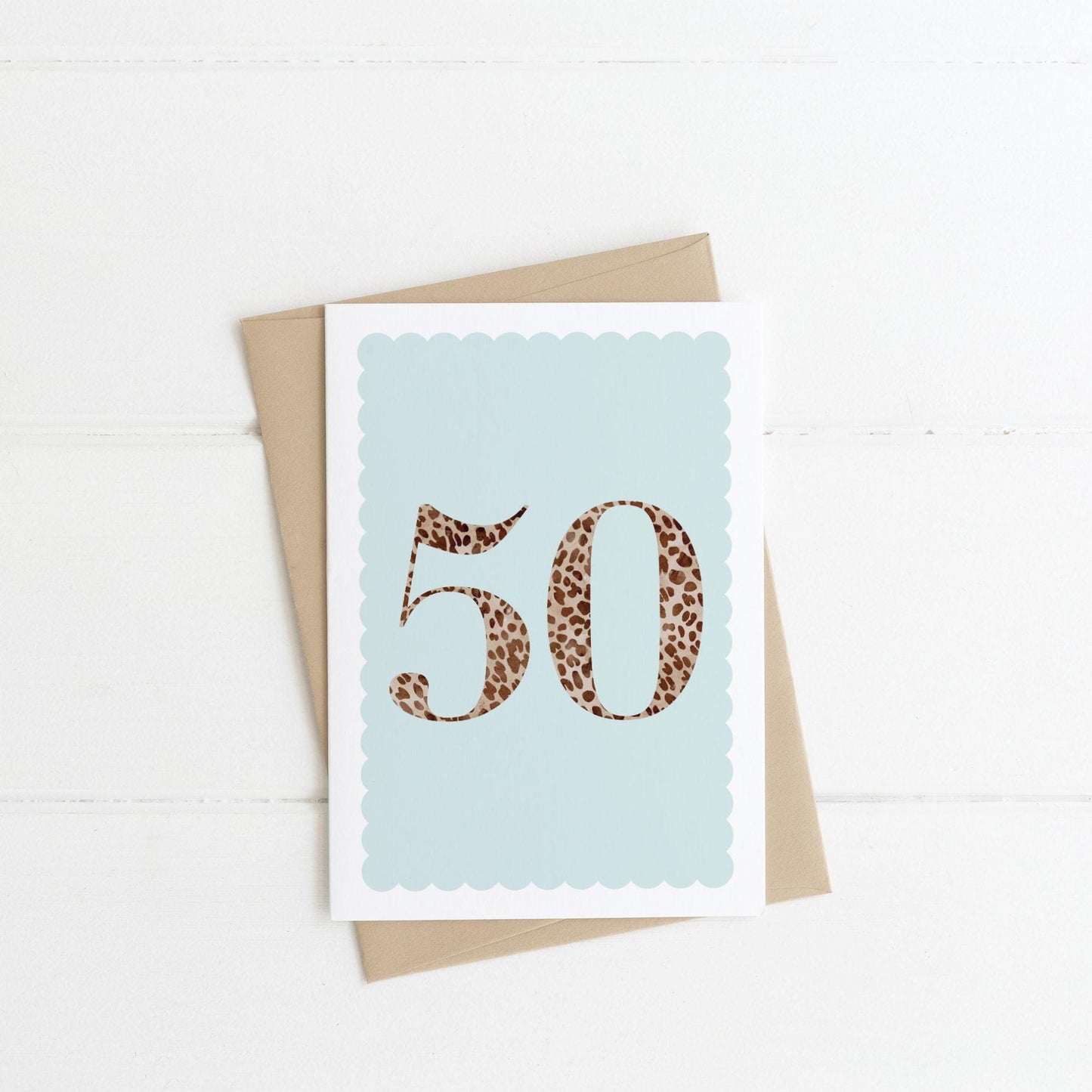 A 50th birthday card with animal print number 50 on a pastel blue background, with a kraft brown envelope