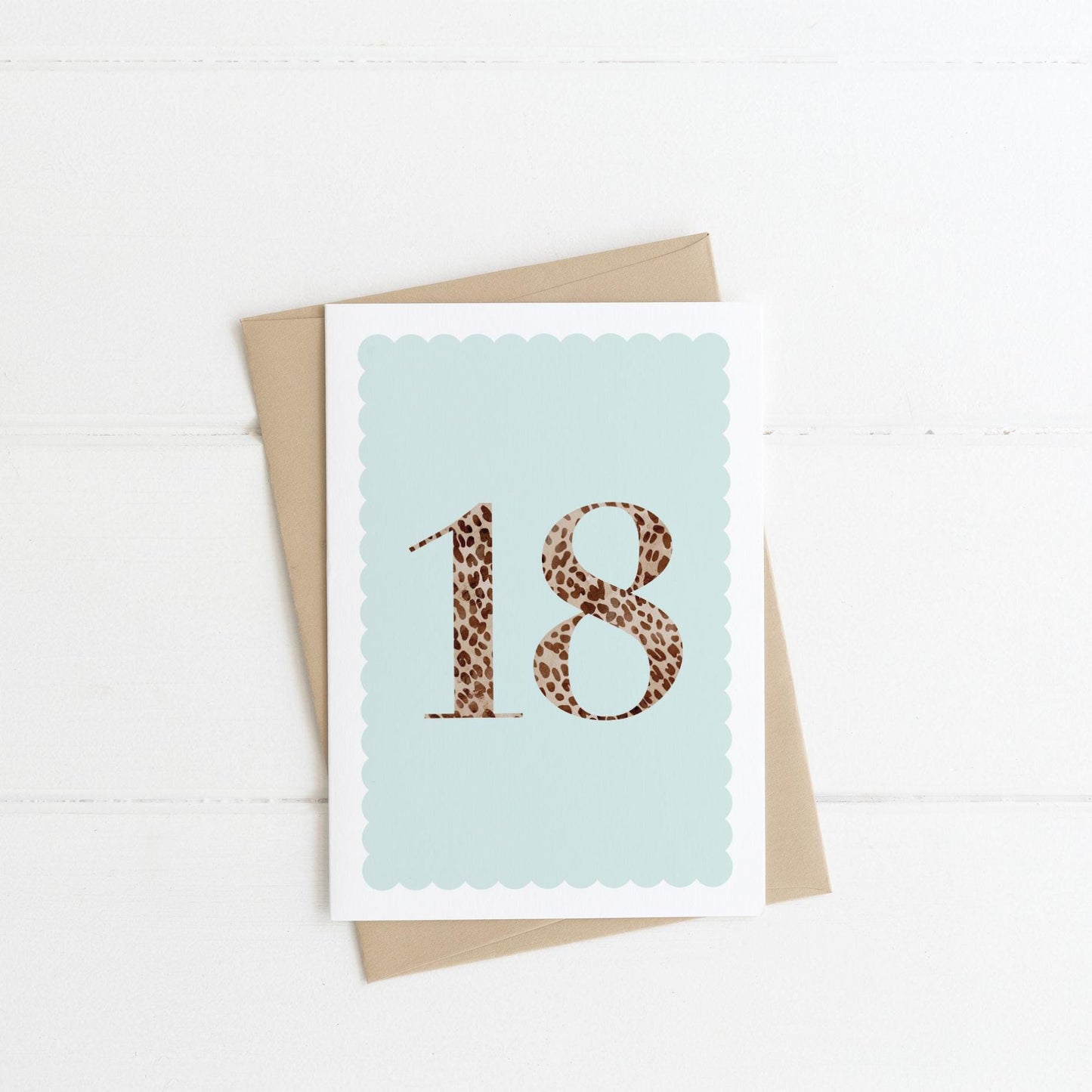 An 18th birthday card with animal print number 18 on a pastel blue background, with a kraft brown envelope
