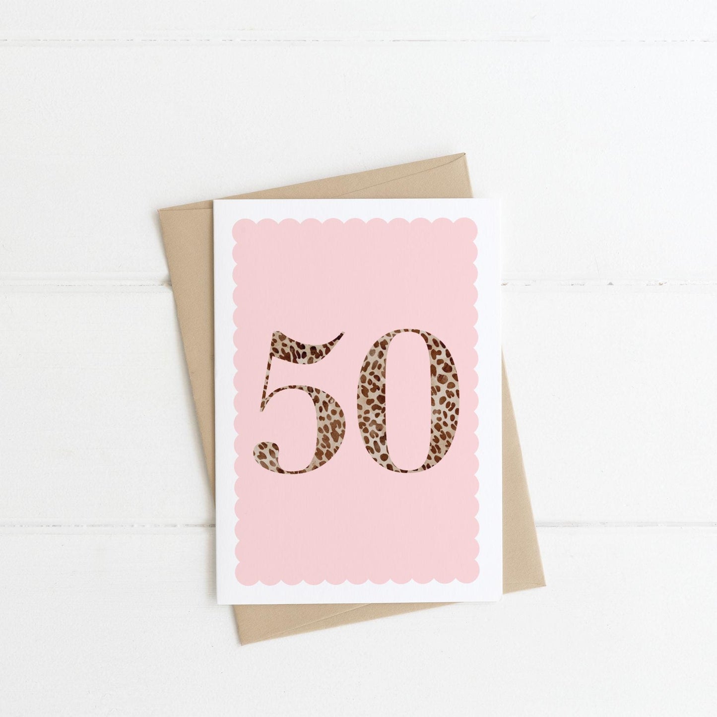 A 50th birthday card with animal print number 50 on a pastel pink background, with a kraft brown envelope