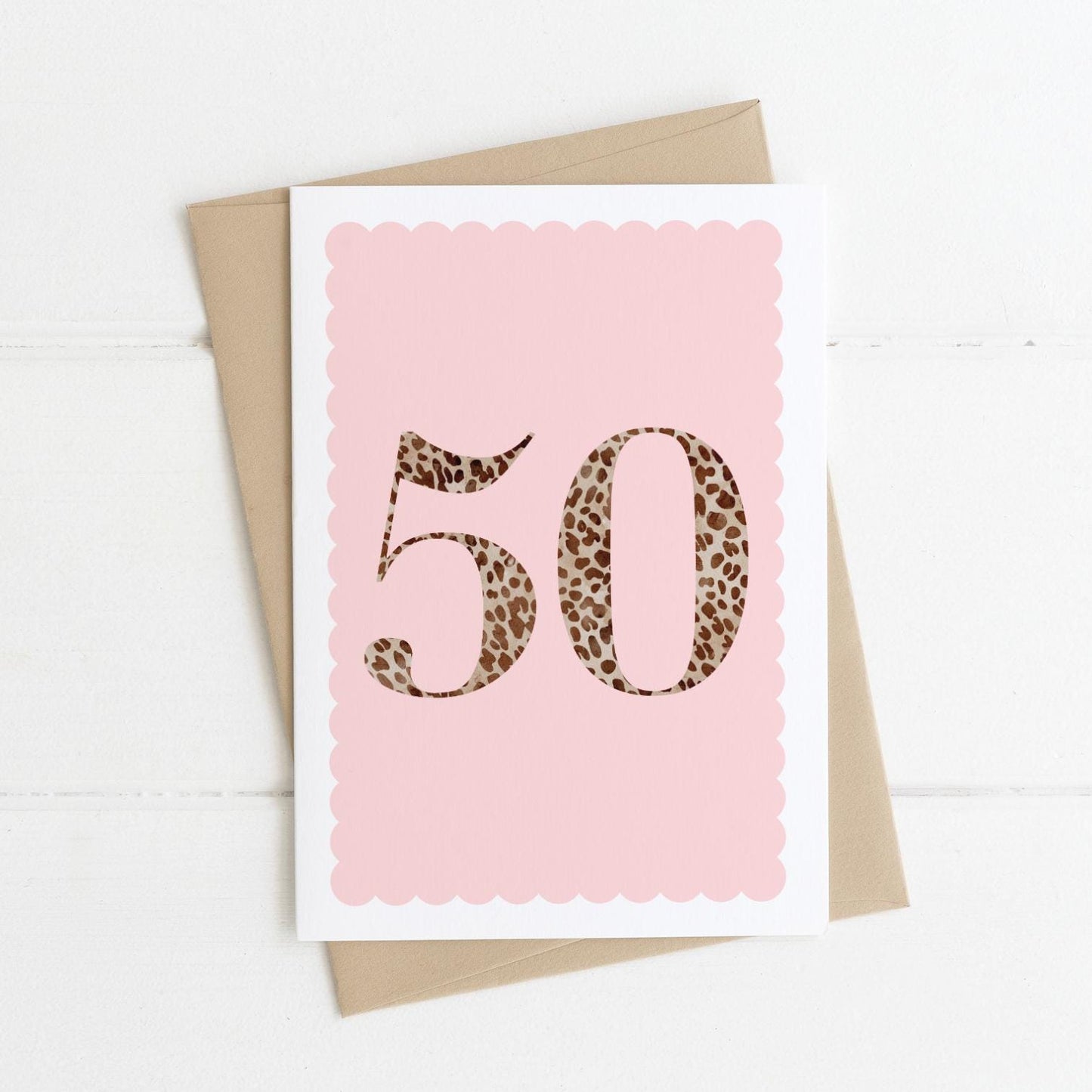 A 50th birthday card with animal print number 50 on a pastel pink background, with a kraft brown envelope