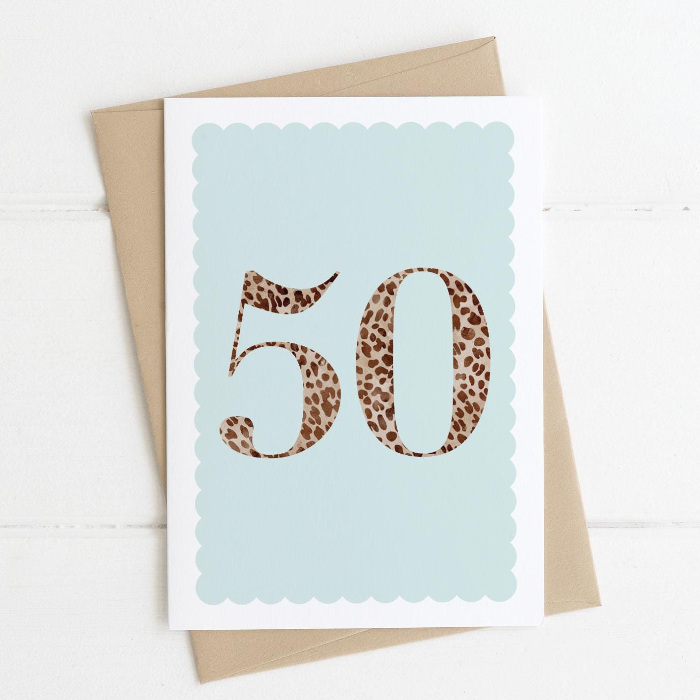 A 50th birthday card with animal print number 50 on a pastel blue background, with a kraft brown envelope