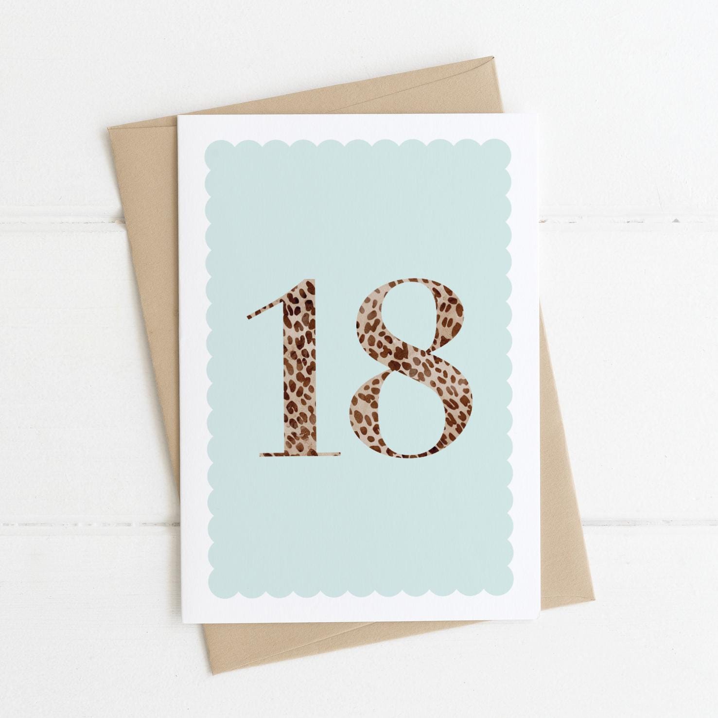 An 18th birthday card with animal print number 18 on a pastel blue background, with a kraft brown envelope