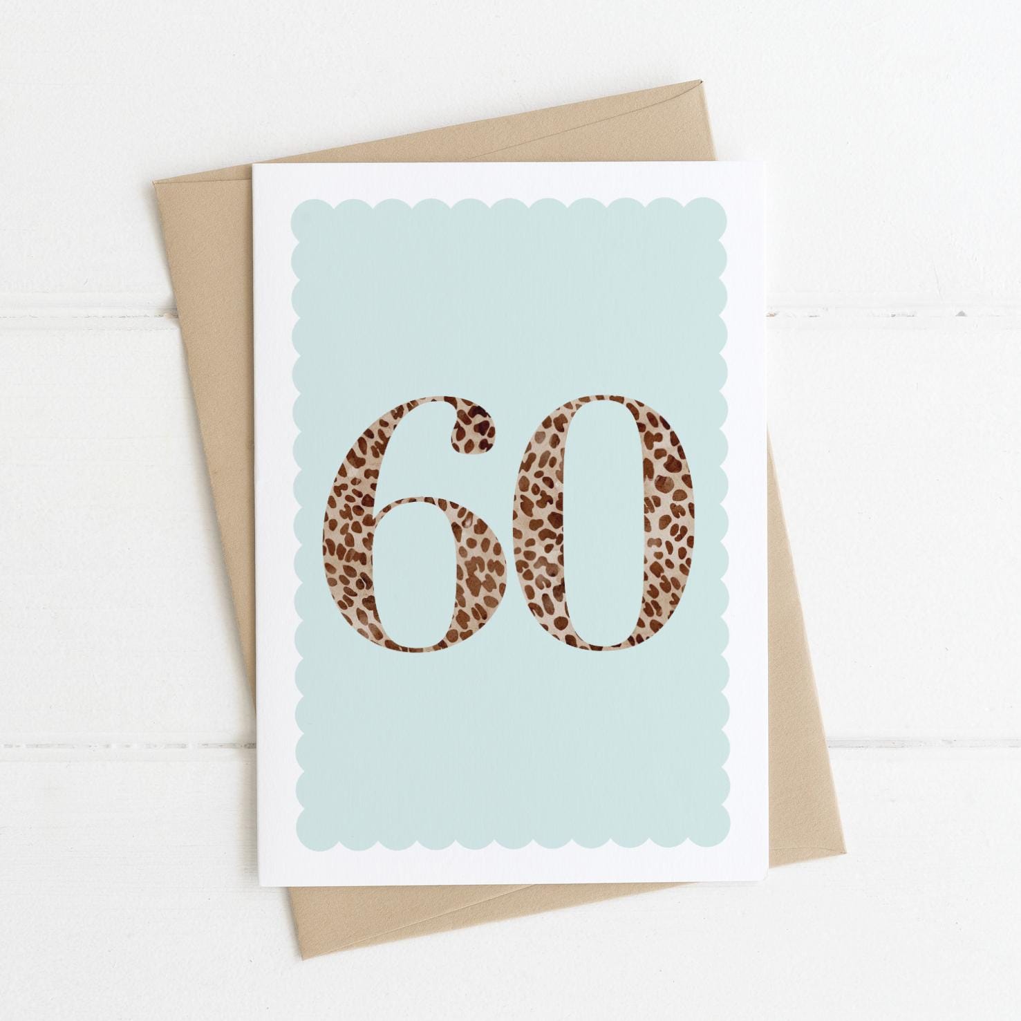A 60th birthday card with animal print number 60 on a pastel blue background, with a kraft brown envelope