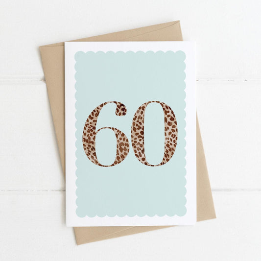 A 60th birthday card with animal print number 60 on a pastel blue background, with a kraft brown envelope