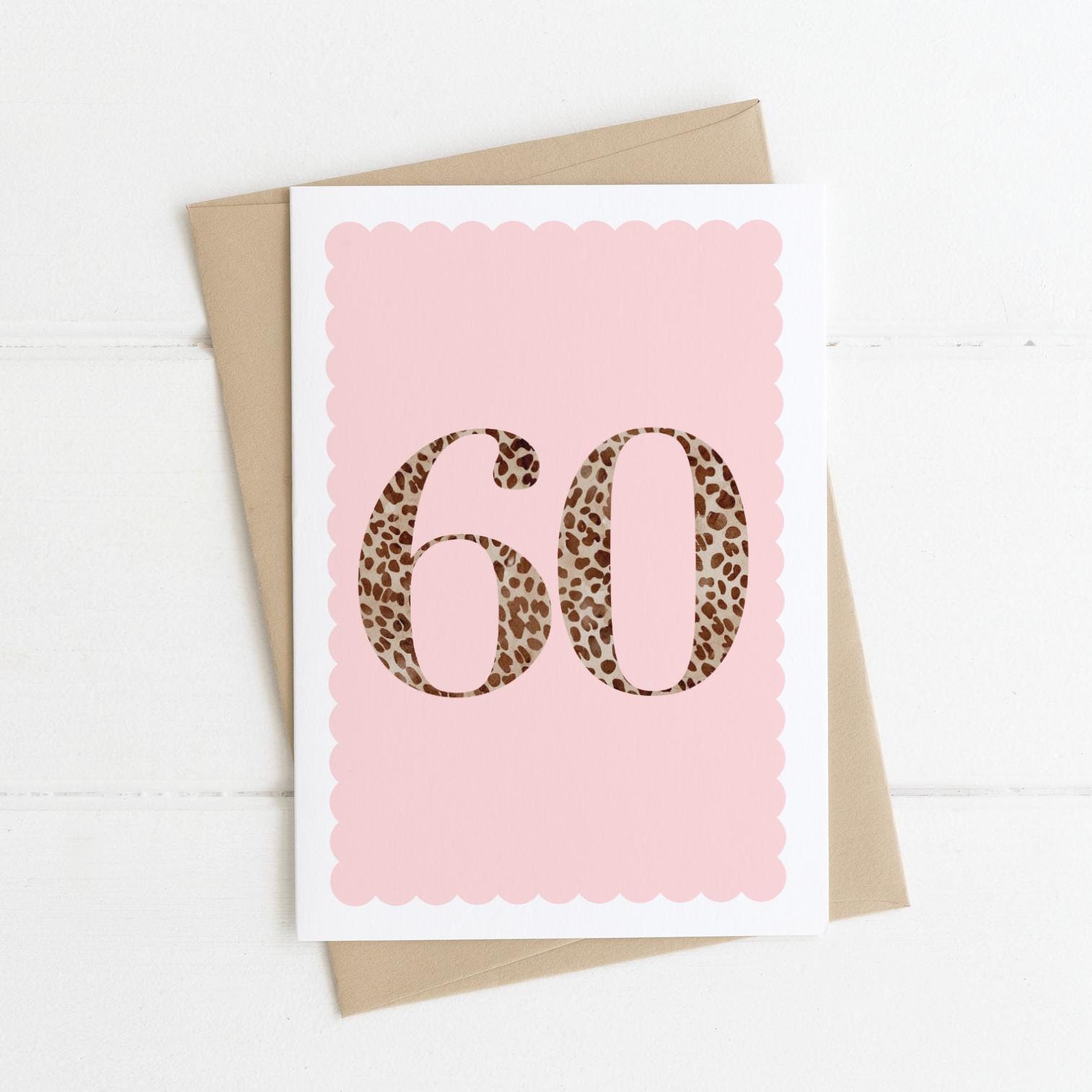 A 60th birthday card with animal print number 60 on a pastel pink background, with a kraft brown envelope