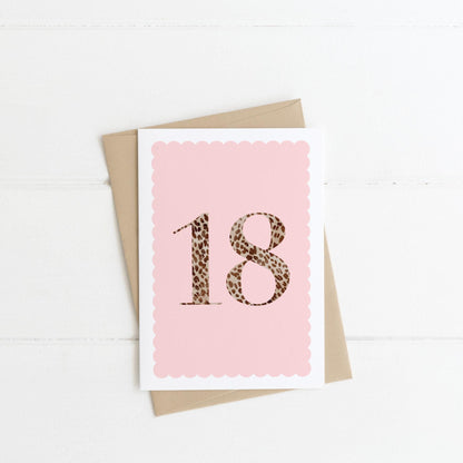 A 18th birthday card with animal print number 18 on a pastel pink background, with a kraft brown envelope