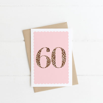 A 60th birthday card with animal print number 60 on a pastel pink background, with a kraft brown envelope